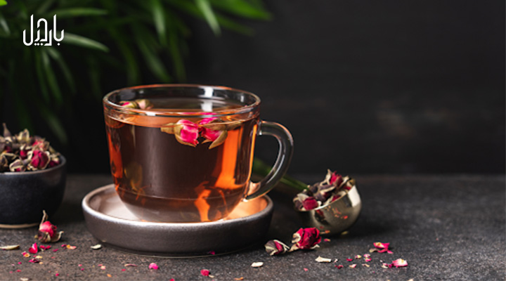 یک فنجان دمنوش گل محمدی با تکه های گل محمدی خشک شده در آن