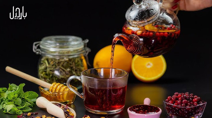 انواع میوه ها و گیاهان در کنار یک قوری چای میوه‌ای در حال پرکردن فنجان