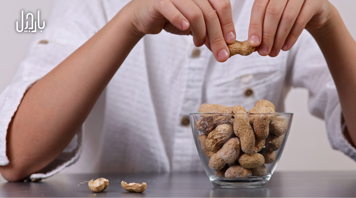 تصویر نزدیک از فردی در حال خوردن بادام زمینی