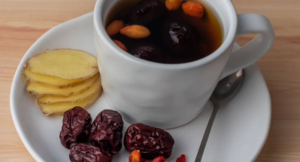 یک فنجان چای عناب به همراه قاشق چای خوری و چند عدد عناب خشک