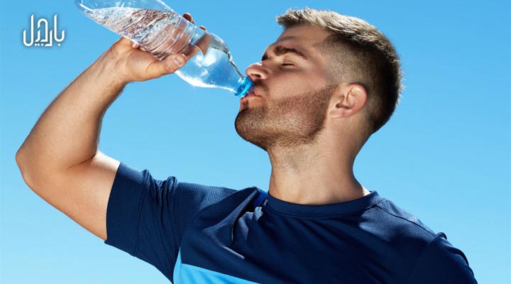 آقایی در حال نوشیدن آب در زیر آفتاب