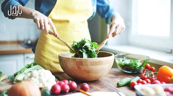 یک خانم در حال درست کردن غذا با سبزیجات تازه