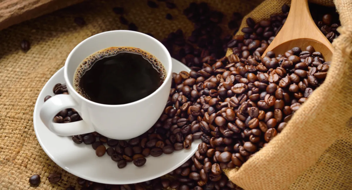 یک فنجان نوشیدنی قهوه و یک گونی دانه قهوه