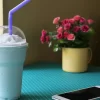 یک فراپه وانیل بر روی میز کنار گلدان و یک تلفن همراه