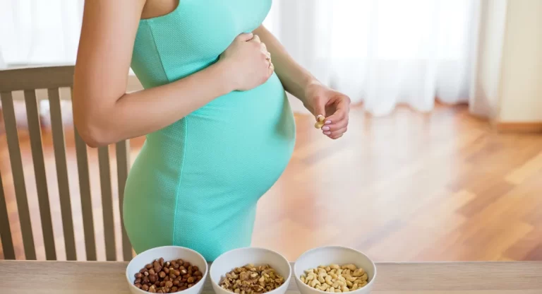 خانمی باردار جلوی میز و سه کاسه آجیل روی میز