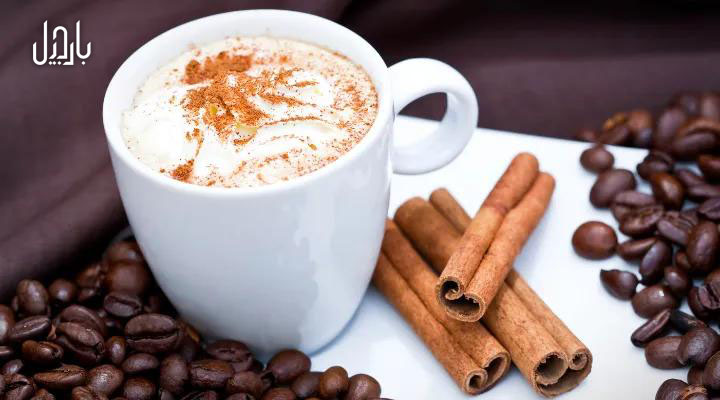 یک فنجان کاپوچینو و مقداری چوب دارچین و دانه قهوه