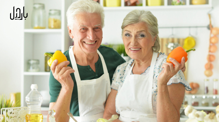 یک خانم و آقای سالمند در حال آشپزی کردن