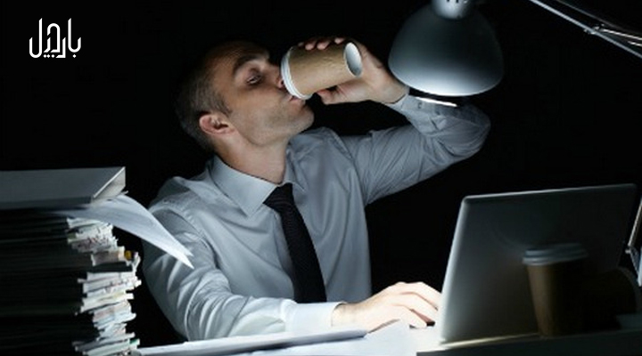 مردی در حال نوشیدن قهوه در شب و پشت میز لپ تاپ
