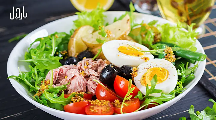بشقاب رژیمی شامل تخم مرغ، تن ماهی، زیتون سیاه، گوجه فرنگی، سیب زمینی و سبزیجات سبز