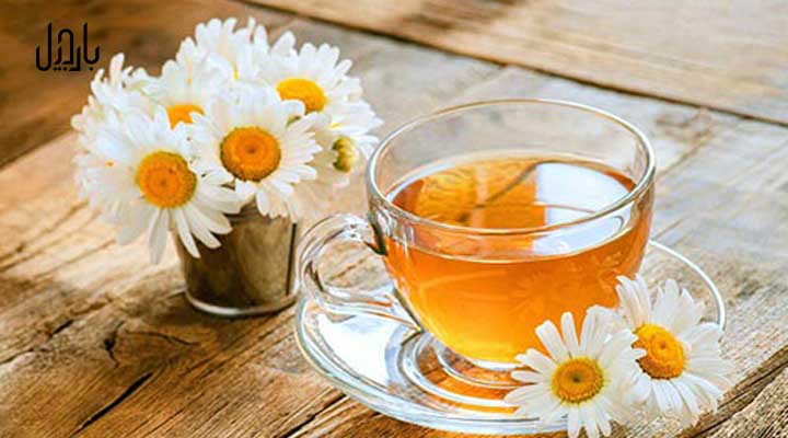 مقداری دمنوش بابونه در فنجان و گل آن