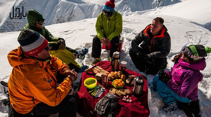 چند کوهنورد در حال خوردن غذا در بالای کوه برفی