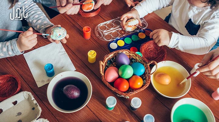 اعضای خانواده دور یک میز درحال رنگ‌کردن تخم مرغ