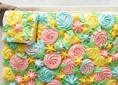 کیک با تزئین خامه به شکل شکوفه در حال برش زدن